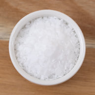 Stearic Acid in a small white container on a wooden surface