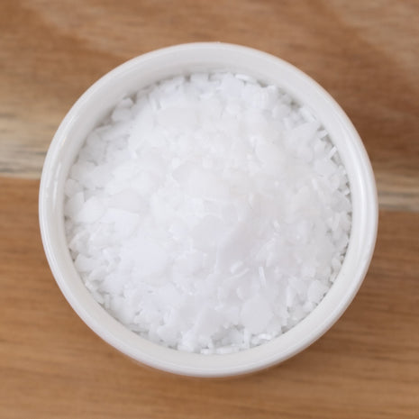 Stearic Acid in a small white container on a wooden surface