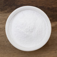 Hyaluronic Acid Powder in a round container on a wooden surface