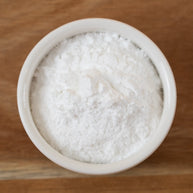 Sodium Cocoyl Isethionate Powder in a small white bowl on a wooden surface