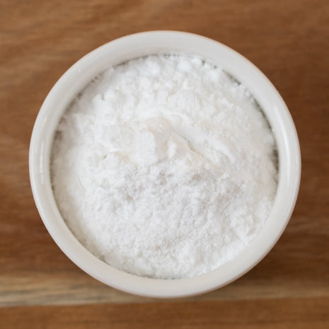 Sodium Cocoyl Isethionate Powder in a small white bowl on a wooden surface