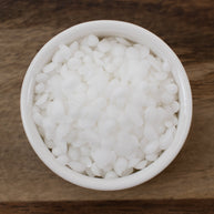 White bowl filled with Emulsifying Wax on a wooden surface