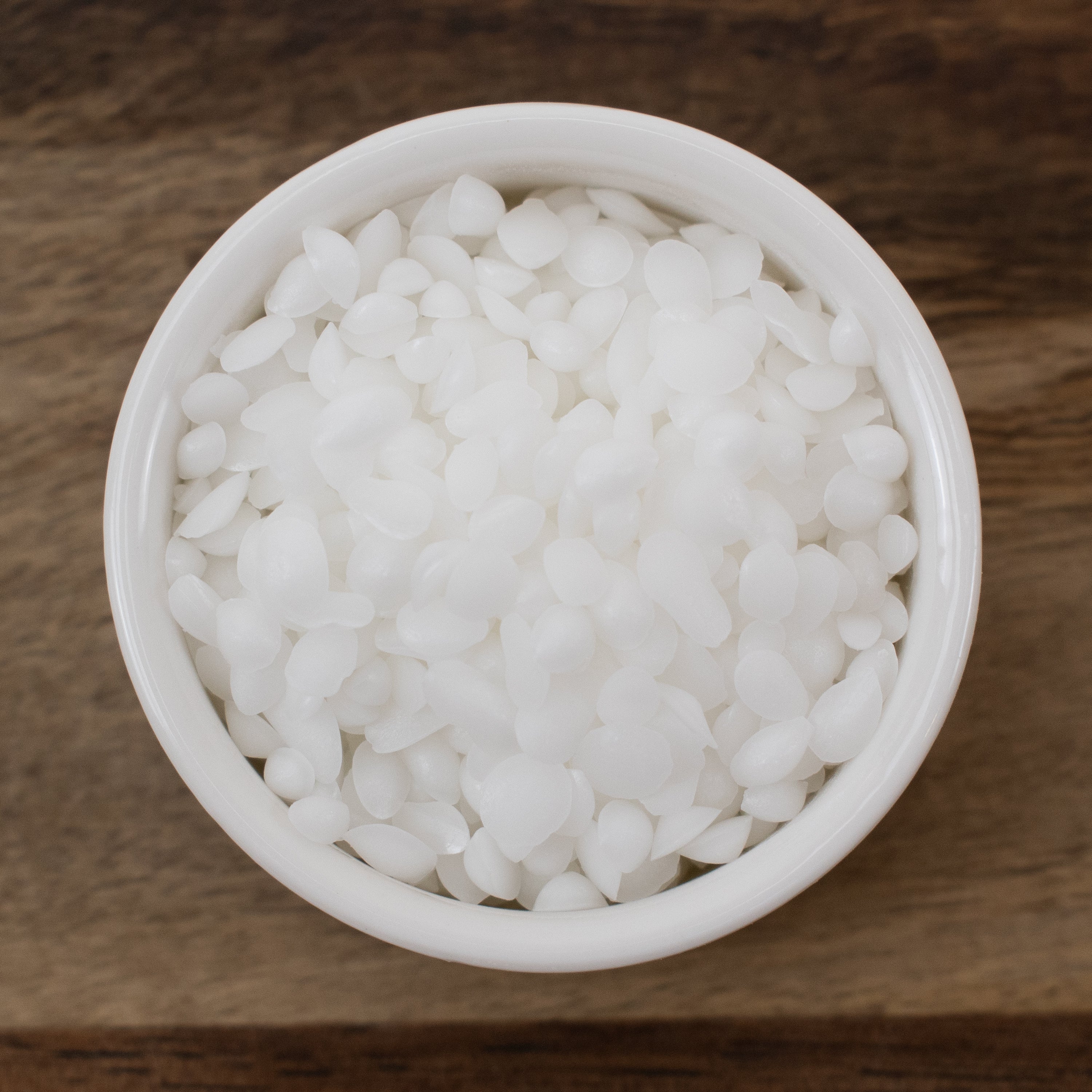 White bowl filled with Emulsifying Wax on a wooden surface