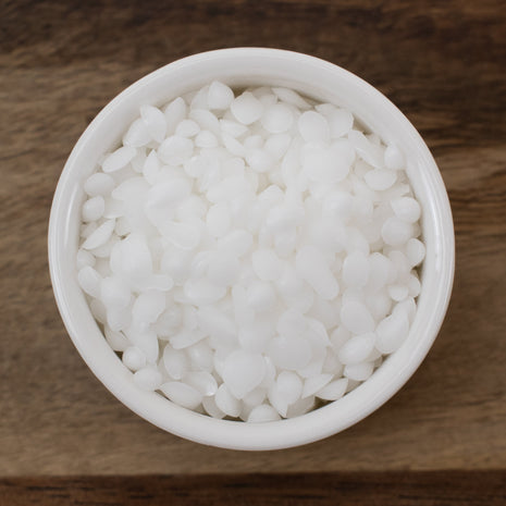 White bowl filled with Emulsifying Wax on a wooden surface